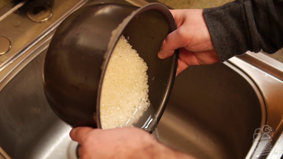 Rice is rinsed over sink in rice cooker pot