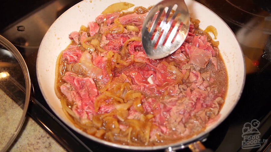 thinly sliced beef is added to onions and sauce in pan