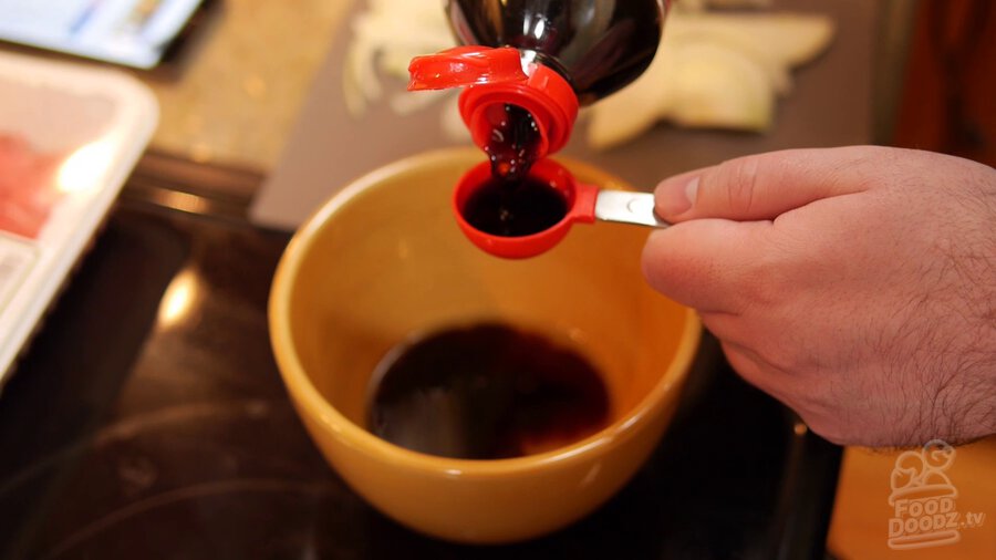 soy sauce is poured into measuring cup before being added to mirin, sugar, dashi mixture in bowl