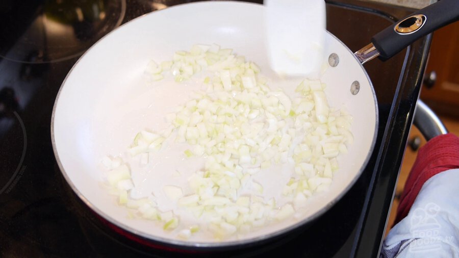 chopped onion is sauted in pan being stirred by large spoon