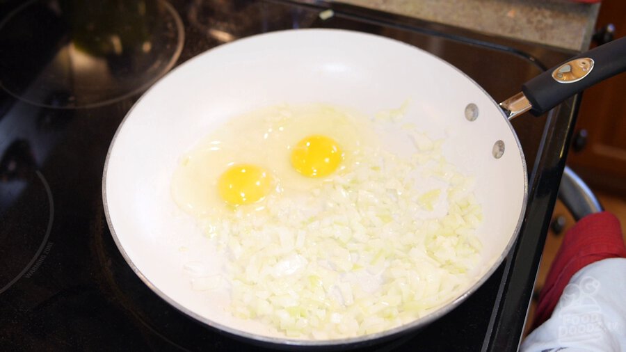two eggs are cracked and added to pan with onion (yolk and whites both)