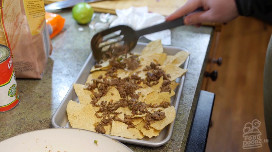 Ground beef mixture is spooned over tortilla chips