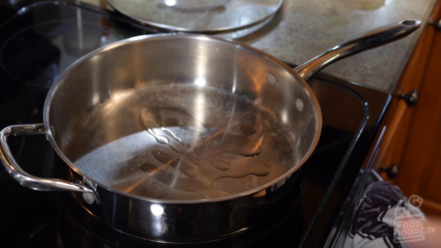 Vegetable oil coats bottom of large stainless steel pan
