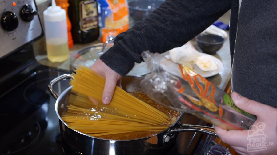 Dry spaghetti pasta is added to pan