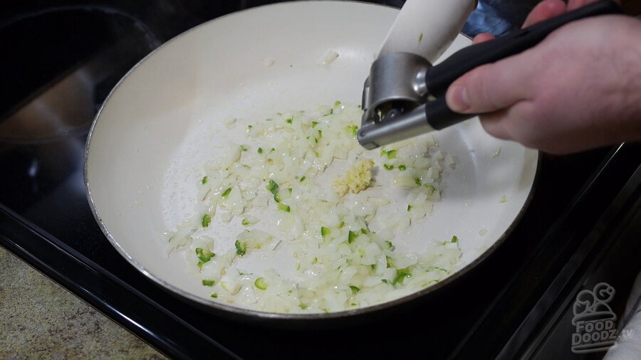 Garlic is minced with garlic press into non-stick skillet