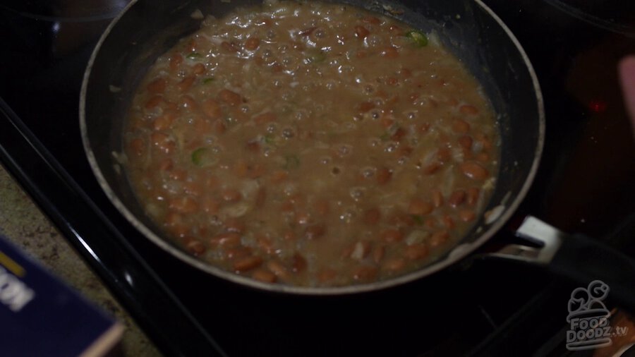 Simmered pinto bean, onion, and serrano pepper mixture is brought to a boil