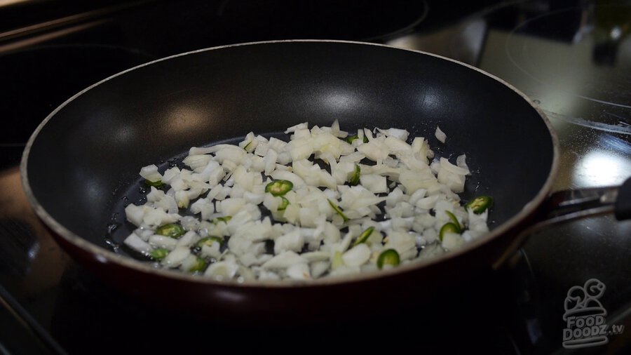 Chopped onion and sliced serrano pepper is added to oiled non-stick skillet