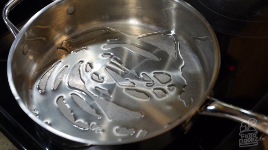 Vegetable oil covers bottom of large steel pan over medium heat