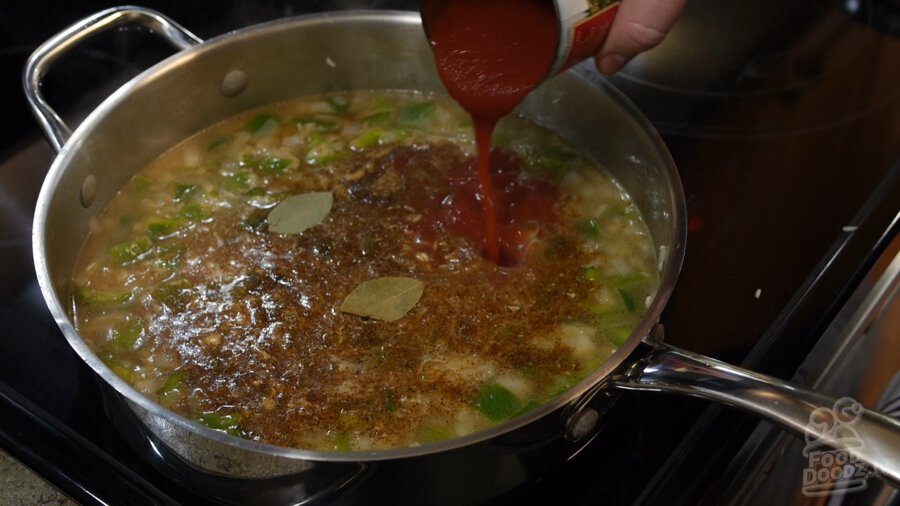 A can of tomato sauce is added to vegetable broth, green bell pepper, onion, and toasted rice mixture