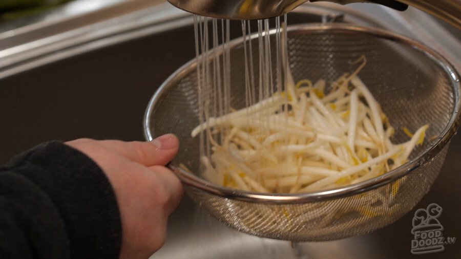 Using faucet to rinse beansprouts in colander over sink