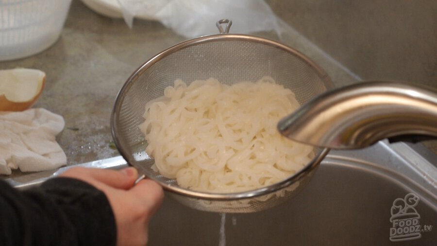 Draining rice boiled noodles in colander over sink