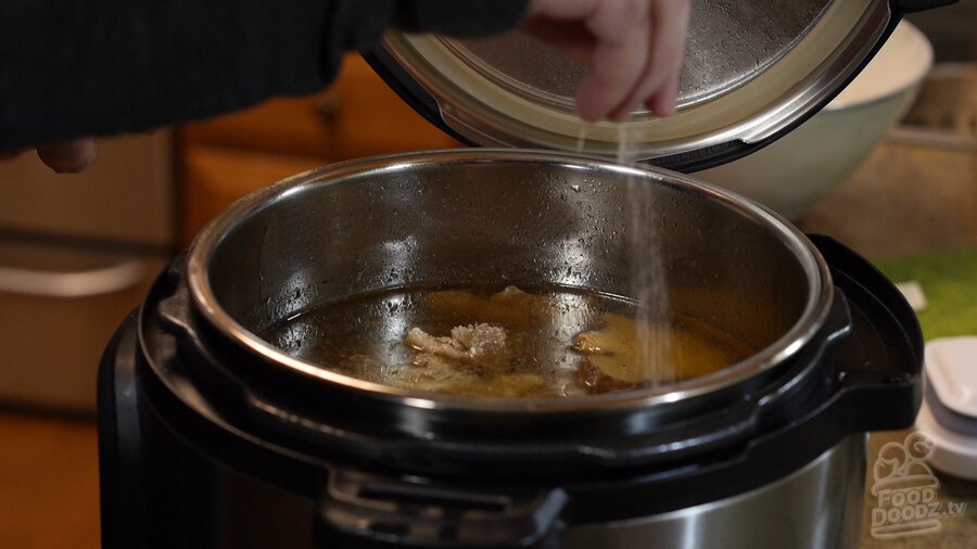 Sprinkling Kosher salt into instant pot full of Vietnamese Pho broth