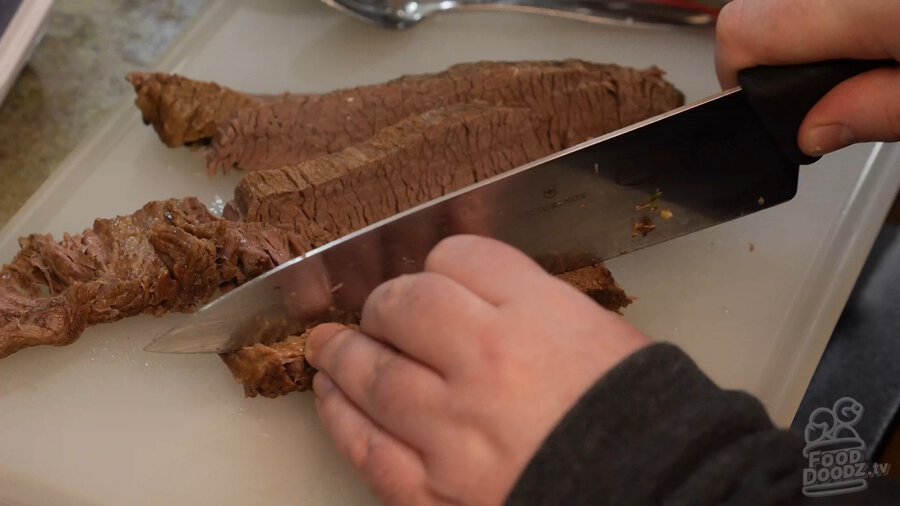 Slicing beef brisket on cutting board after removing from Vietnamese Pho broth cooked in instant pot