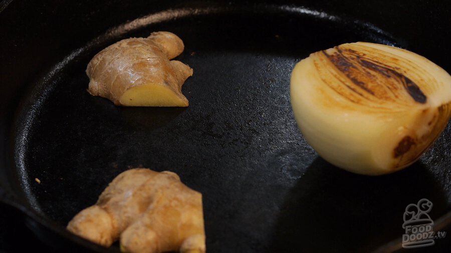 Charring onion and ginger halves in cast iron skillet