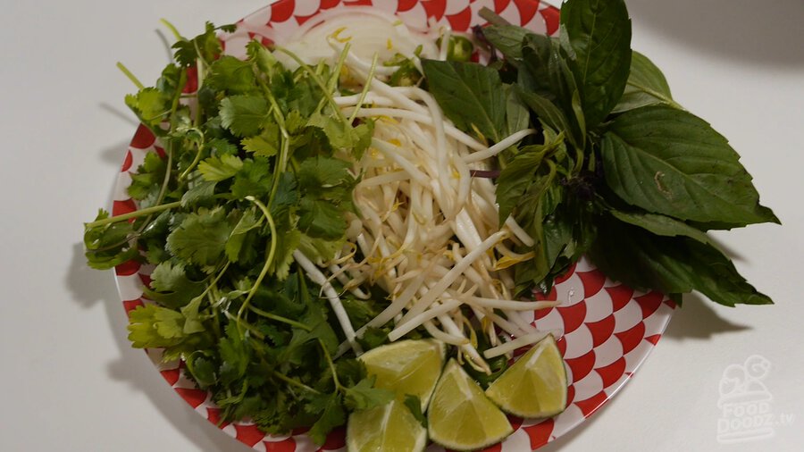 Vietnamese Pho garnishes prepared on decorative plate (cilantro, beansprouts, lime, Thai basil, sliced serranos, and onion)