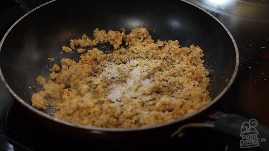 Dried oregano, basil, red pepper flakes, garlic powder, and salt added to pan of sauteing textured vegetable protein (TVP)