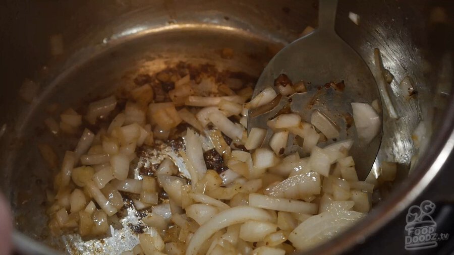Onions sauteing in pot beef was removed from. Stirring with large spoon.