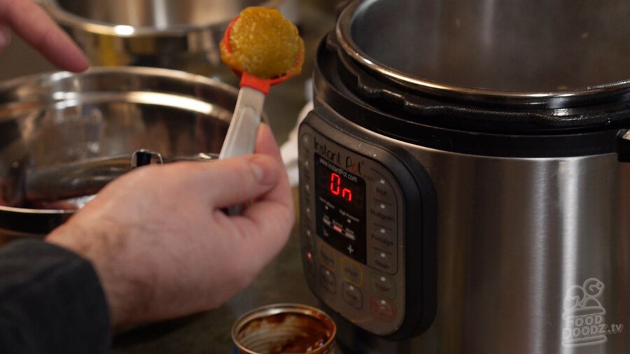 Hand scooping liquid chicken bouillon into pot