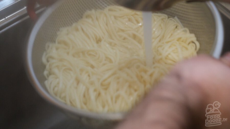 Rinsing a colander of noodles off