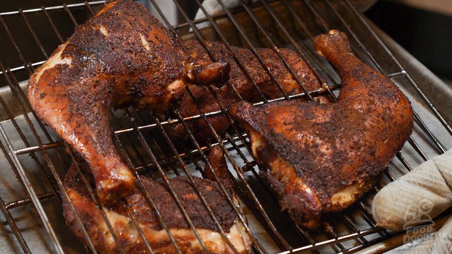 finished chicken quarters being pulled out of the smoker