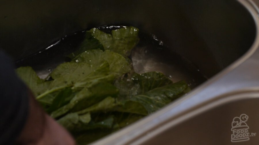 Washing greens in a sink filled with water