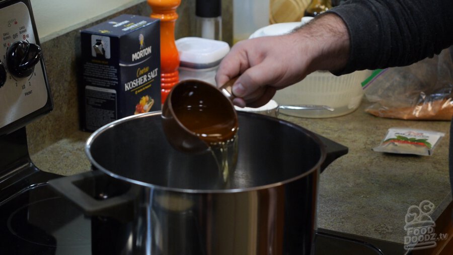1 cup of oil being added to a hot stock pot