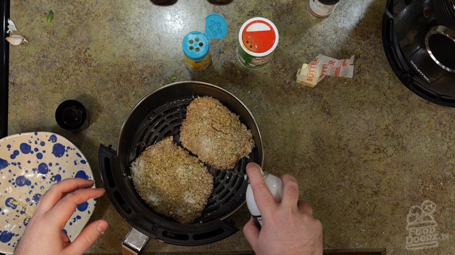 Raw Chicken fried steaks being sprayed with oil