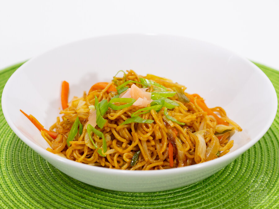 A delectable bowl of vegetable yakisoba piled high and topped with pickled ginger and green onions