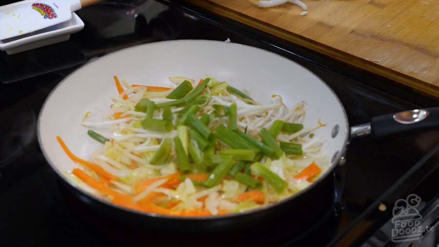 Adding the green onions and bean sprouts to the pan