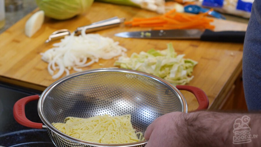 Opening noodle packets into a colander to be rinsed