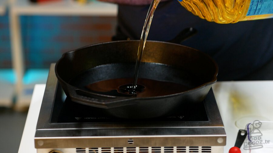 Adding oil to a large cast iron skillet.
