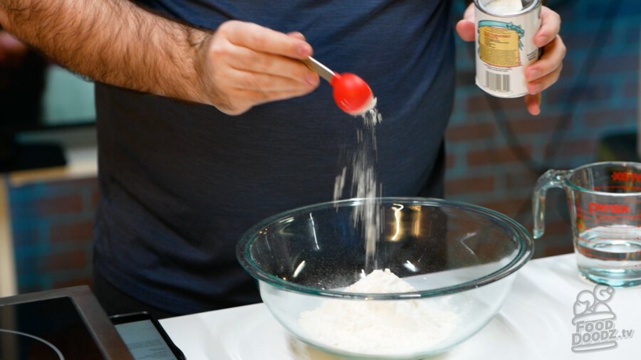 Adding baking powder to flour and salt in bowl