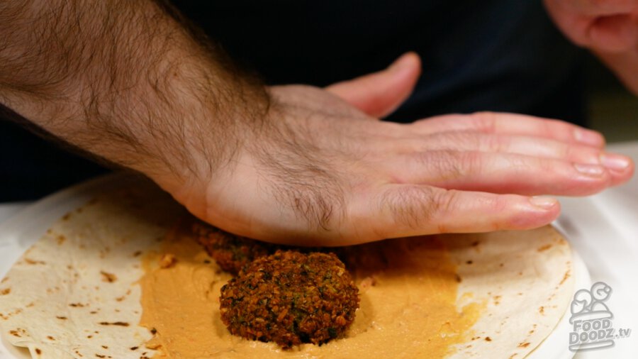 Smashing falafel down into hummus