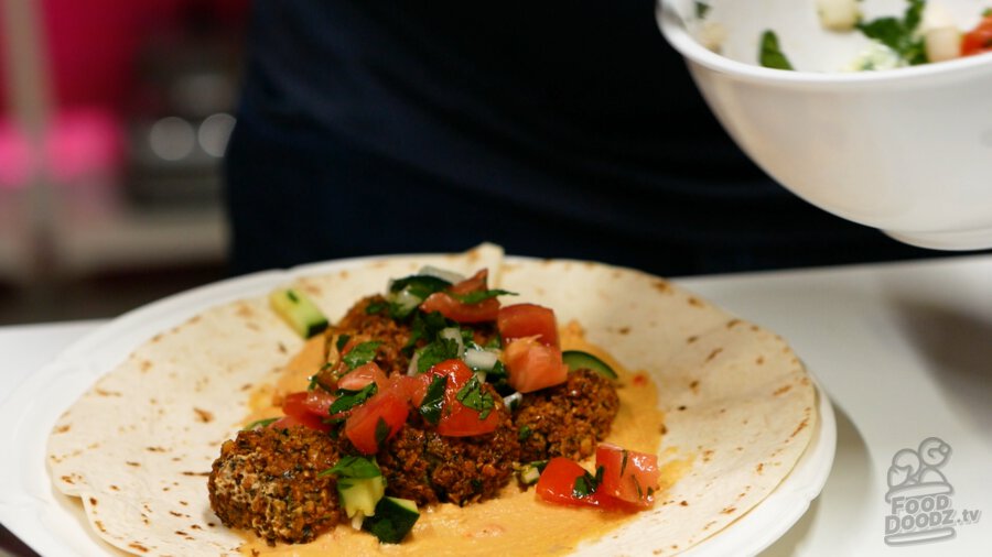 Topping smashed falafels with cucumber tomato salad