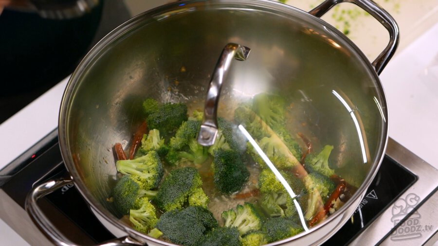 A lid placed over the pan with the broccoli in it