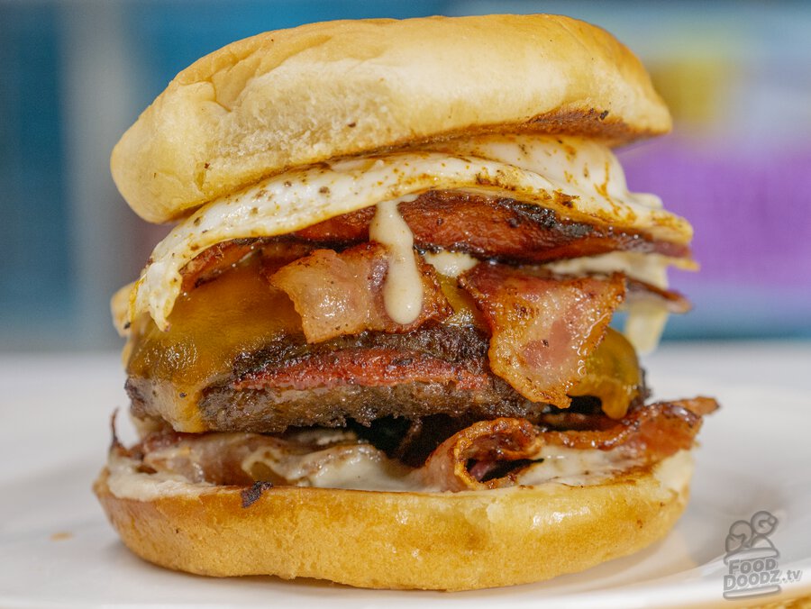 A delicious and hearty breakfast burger with sausage, bacon, a fried egg, gravy, and cheese.
