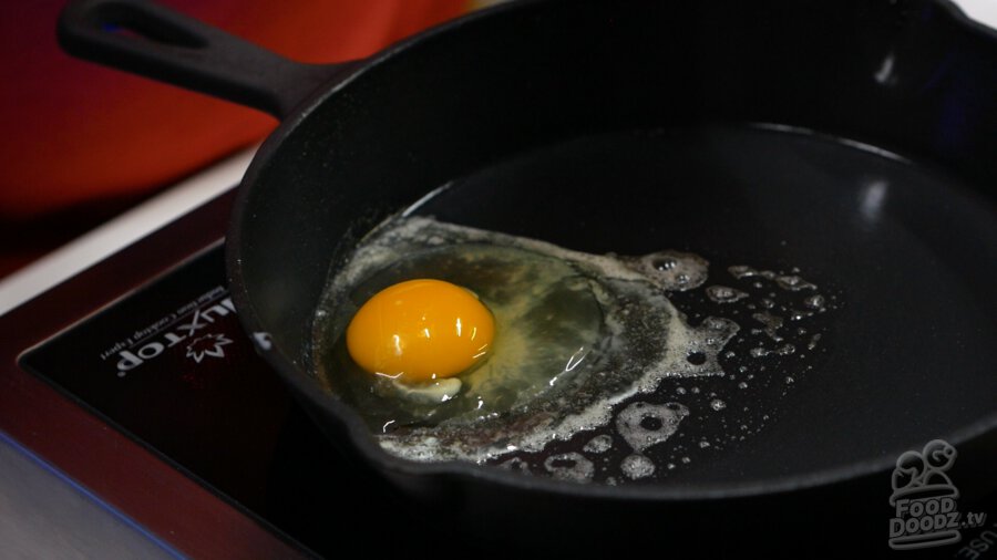 Our freshly cracked egg into our hot buttered pan
