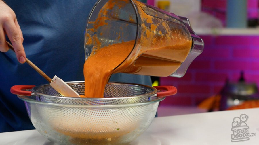 Pouring gazpacho into a colander