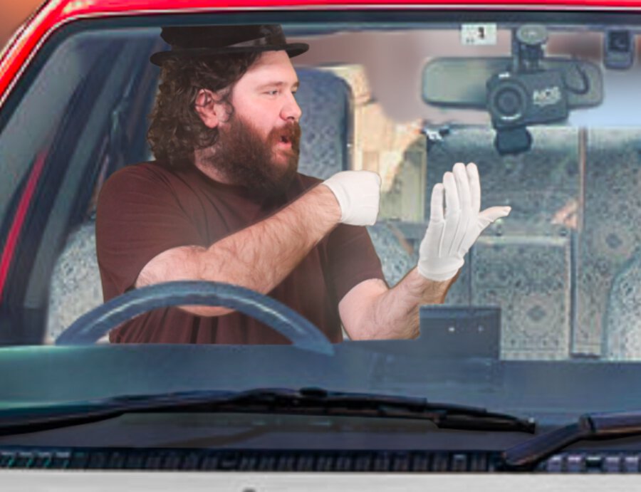 Adam in top hat and white gloves driving Japanese taxi cab while watching his phone