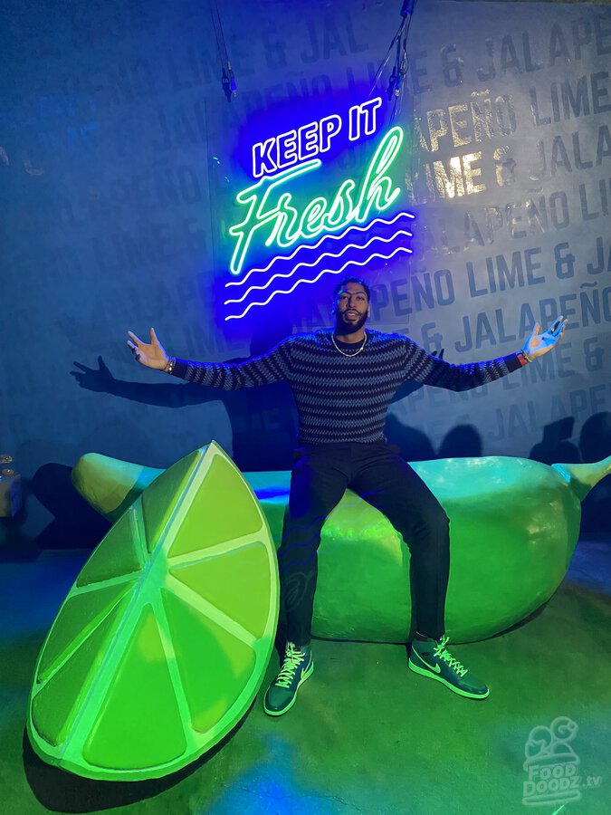 Anthony Davis at Lime & Jalapeno Ruffles chips launch event sitting on giant lime