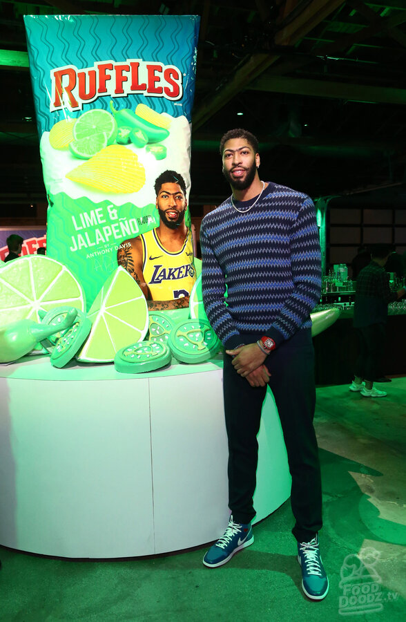 Anthony Davis at Lime & Jalapeno Ruffles chips launch event standing next to giant bag of Ruffles chips