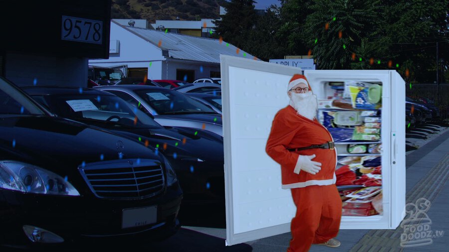 Austin dressed as Santa slapping the top of a freezer in front of a used car lot