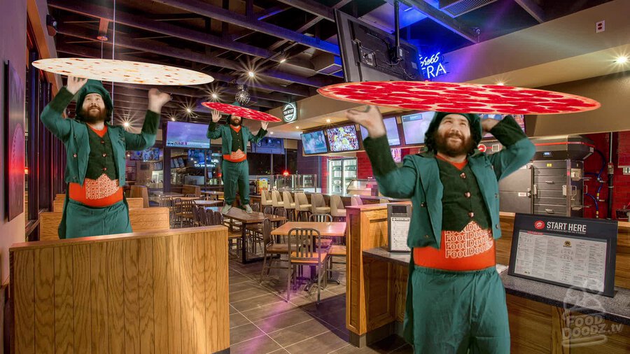 Adam dressed as leprechaun performing circus act of trying to keep tortilla and Pizza Hut weighted blankets spinning above his head inside of a Pizza Hut restaurant